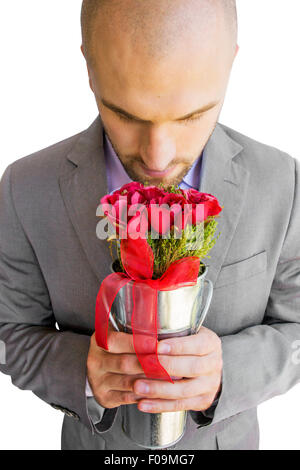 Uomo in tuta holding bouquet di rose rosse in un vaso Foto Stock