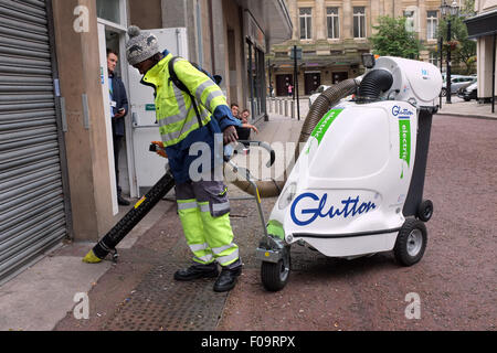 Operativa maschio utilizzando un ghiottone rifiuti elettrici street aspirapolvere a Bolton, Lancashire, Inghilterra, Regno Unito Foto Stock