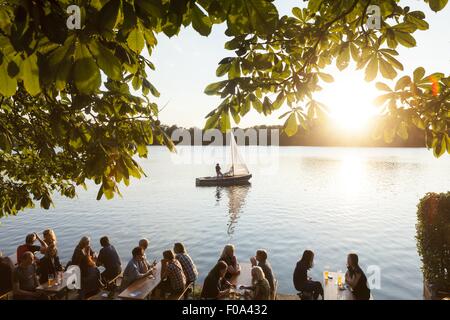 La gente seduta a Maschseefest giardino della birra con il traghetto a sfondo, Hannover, Germania Foto Stock