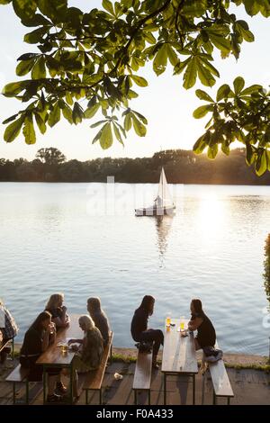 La gente seduta a Maschseefest giardino della birra con il traghetto a sfondo, Hannover, Germania Foto Stock