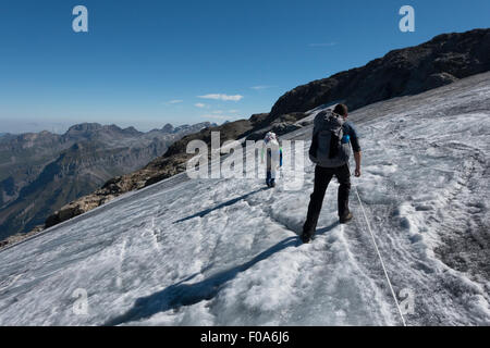 BASE Wingsuit ponticelli sono arrampicata su roccia tra un ghiacciaio e neve per scoprire il jump-off point e preparare la loro tuta. Foto Stock