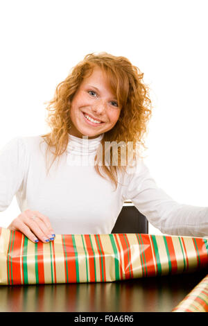 Giovani redhaired sorridente donna incarto regali di natale Foto Stock