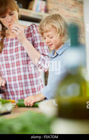 Madre e figlio per affettare cetrioli in cucina Foto Stock