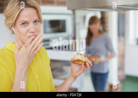 Le donne di mangiare la torta in cucina Foto Stock