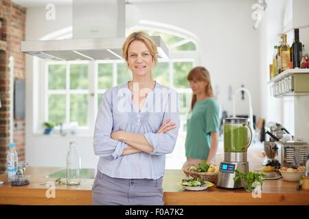 Le donne accanto a blender pieno di verde frullato vegano Foto Stock