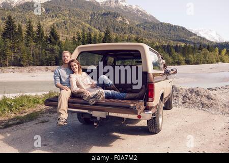 Giovane seduto sul retro del pick up truck, guardando la telecamera, Wallgau, Baviera, Germania Foto Stock