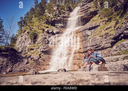 Madre e due figli, esplorare, accanto a cascata Foto Stock