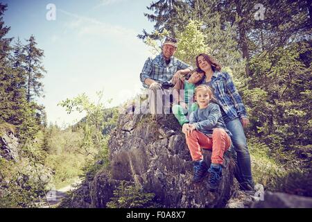 Ritratto di famiglia seduta su roccia nella foresta Foto Stock