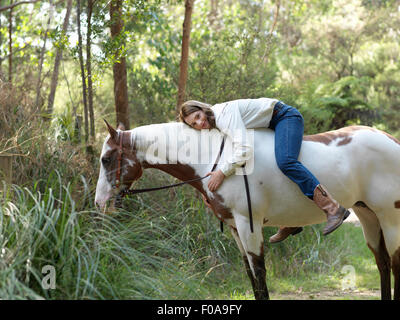 Ritratto di ragazza adolescente abbracciando cavallo mentre bareback riding Foto Stock