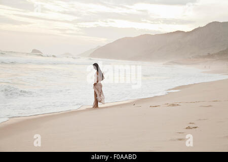 Metà donna adulta camminando lungo la spiaggia Foto Stock