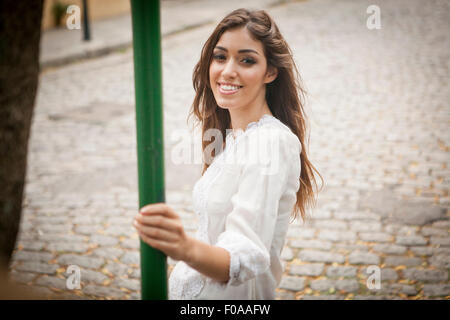 Ritratto di giovane donna, sorridente, tenendo pole Foto Stock