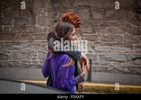 Giovane camminando lungo la strada, le braccia intorno a ciascun altro Foto Stock