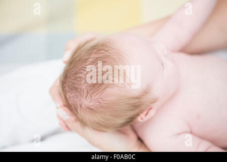 Madre cullano il bambino nelle braccia Foto Stock