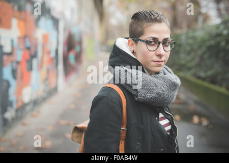 Adolescente sulla strada, muro di graffiti in background Foto Stock