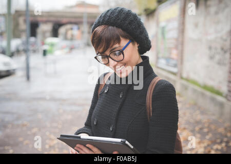 Giovane donna con tavoletta digitale su strada Foto Stock