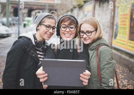 Le tre sorelle tenendo selfie su strada Foto Stock