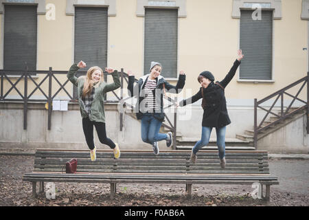 Le tre sorelle saltando su una panchina nel parco Foto Stock