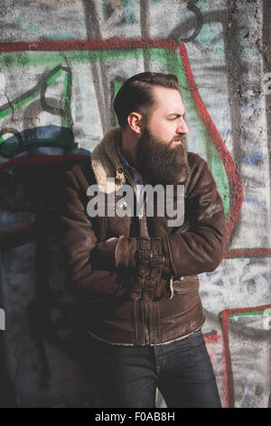 Giovane uomo barbuto dal muro di graffiti Foto Stock