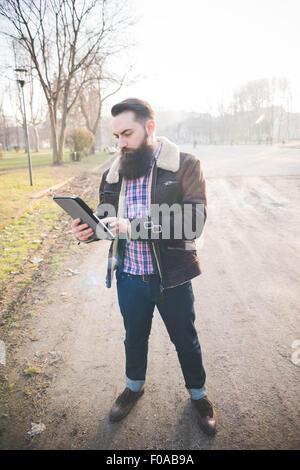 Giovane uomo barbuto con tavoletta digitale in posizione di parcheggio Foto Stock