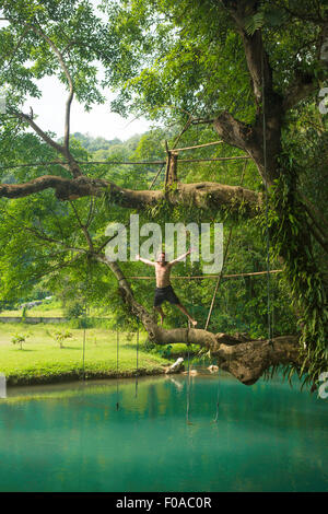 Uomo maturo jumping metà aria nella laguna turchese, Vang Vieng, Laos Foto Stock