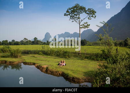 Due amiche relax su Nam Song riverbank, Vang Vieng, Laos Foto Stock