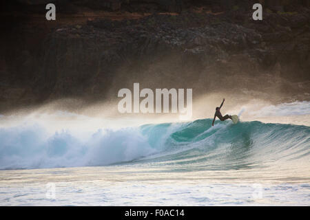 Stagliano giovane uomo onda surf al tramonto, Fuerteventura, Spagna Foto Stock