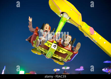 Fratello e Sorella mezza aria su fairground ride di notte Foto Stock