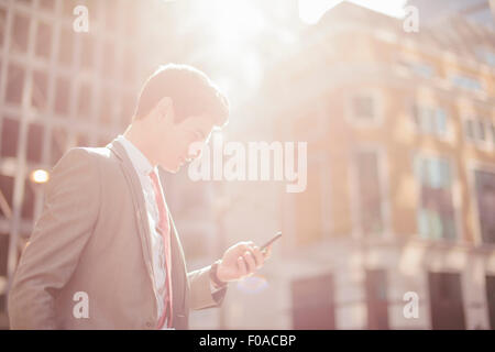 Città giovane imprenditore la lettura di testi sullo smartphone mentre si camminava Foto Stock