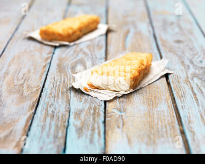 Due fritti chunky martoriata eglefino pezzi sul tavolo di legno Foto Stock