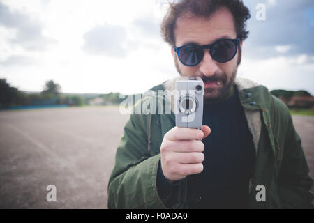 Ritratto di metà uomo adulto che posano con vintage movie camera sulla massa di rifiuti Foto Stock