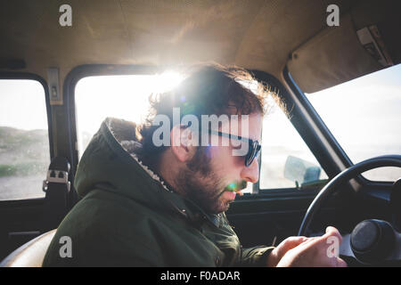 Uomo in auto presso la spiaggia la laminazione di una sigaretta Foto Stock