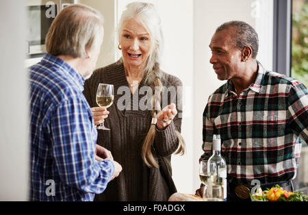 Senior amici parlano in cucina con il vino Foto Stock