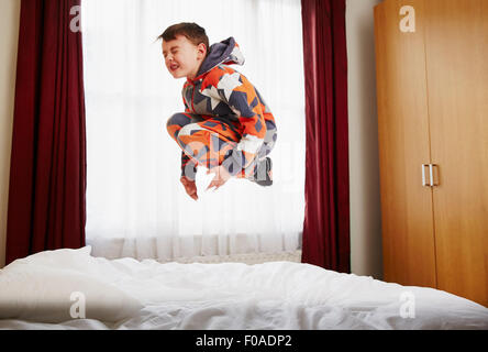 Giovane ragazzo saltando sul letto Foto Stock