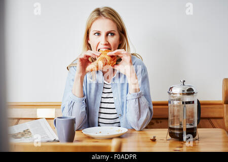 Metà donna adulta mangiare croissant Foto Stock