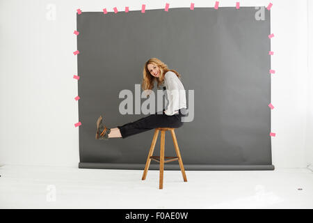 Donna su uno sgabello davanti dei fotografi di sfondo Foto Stock