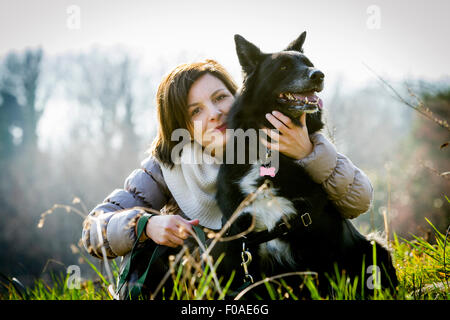 Ritratto di metà donna adulta con braccio intorno al suo cane nel campo Foto Stock