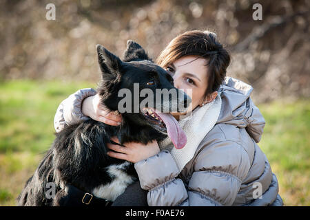 Ritratto di metà donna adulta baciare il suo cane nel campo Foto Stock