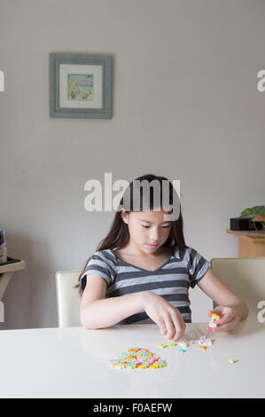 Ragazza alla tabella a giocare con puzzle Foto Stock