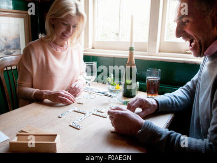 Paio di bere e di riproduzione di domino nel pub Foto Stock