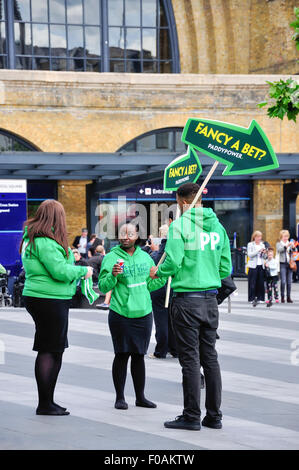 Giovane "PaddyPower' team con segni al di fuori dalla stazione ferroviaria di King's Cross, King's Cross London Borough of Camden, Londra, Inghilterra Foto Stock