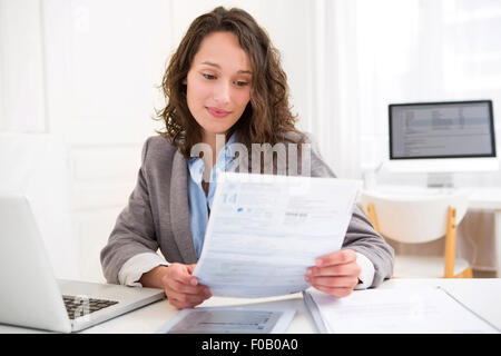 Vista di una giovane donna attraente facendo di documenti cartacei Foto Stock