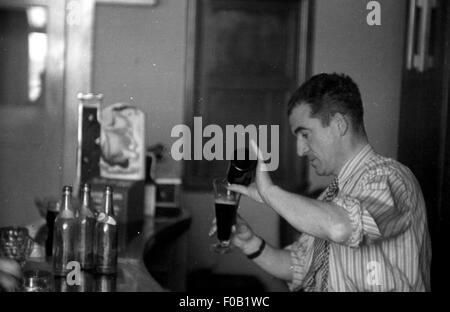 Un uomo versando un bicchiere di birra Foto Stock