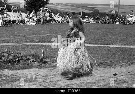 Un po' di giovane ragazza in un abito di Hawaiian e fiori intorno al collo in corrispondenza di un evento. Foto Stock