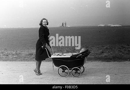 Una donna spingendo un bambino in un contenuto della PRAM Foto Stock