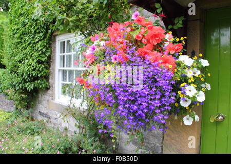 Nei cestini appesi telaio porta ad un tradizionale cottage in pietra nel Peak District, Derbyshire, Regno Unito Inghilterra in estate Foto Stock