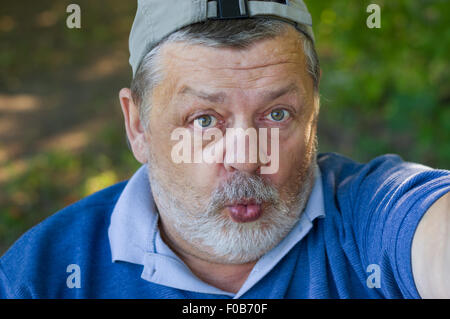 Ritratto di un uomo anziano chiedendo e rendendo la seconda selfie nella sua vita Foto Stock