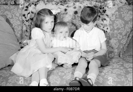 Tre bambini seduti su un divano Foto Stock