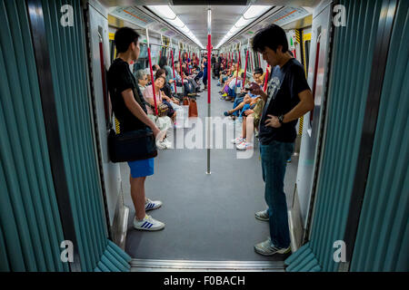 I passeggeri a bordo di una vettura della metropolitana di Hong Kong, Cina Foto Stock