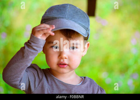 Bambina a mettere su il suo cappello in estate Foto Stock