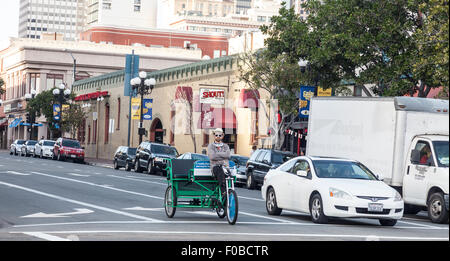 Ciclo driver Rickshaw rilassa mentre arrestato in corrispondenza di una giunzione sul 4° Avenue & Market Street, San Diego vicino a gridare la casa. Stati Uniti d'America Foto Stock
